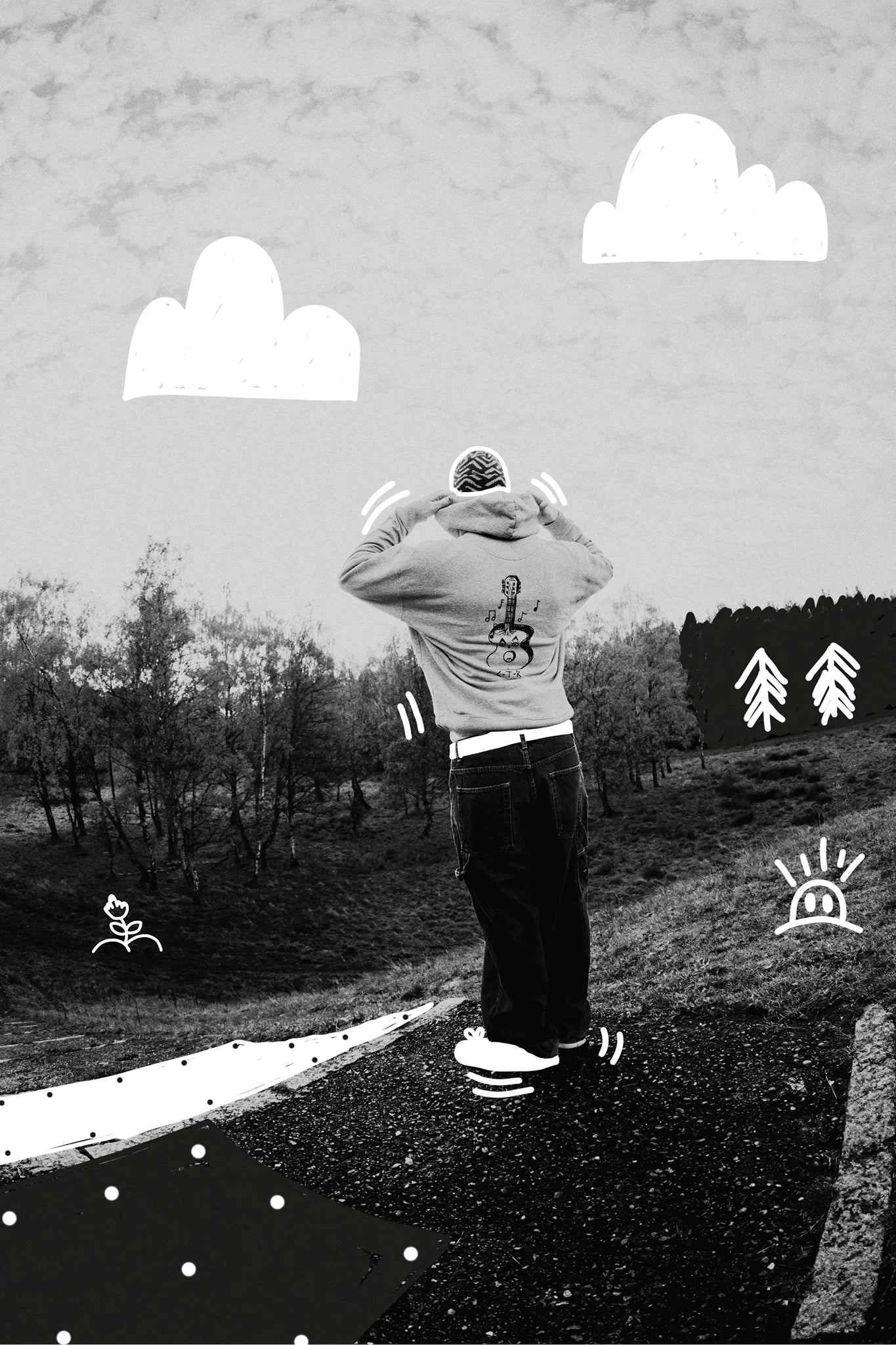 Alt text:
Black-and-white outdoor scene showing a person from behind adjusting the hood of a **Jovandi hoodie** featuring a guitar illustration on the back. The landscape is overlaid with playful white doodles, including clouds, trees, and small character sketches.

