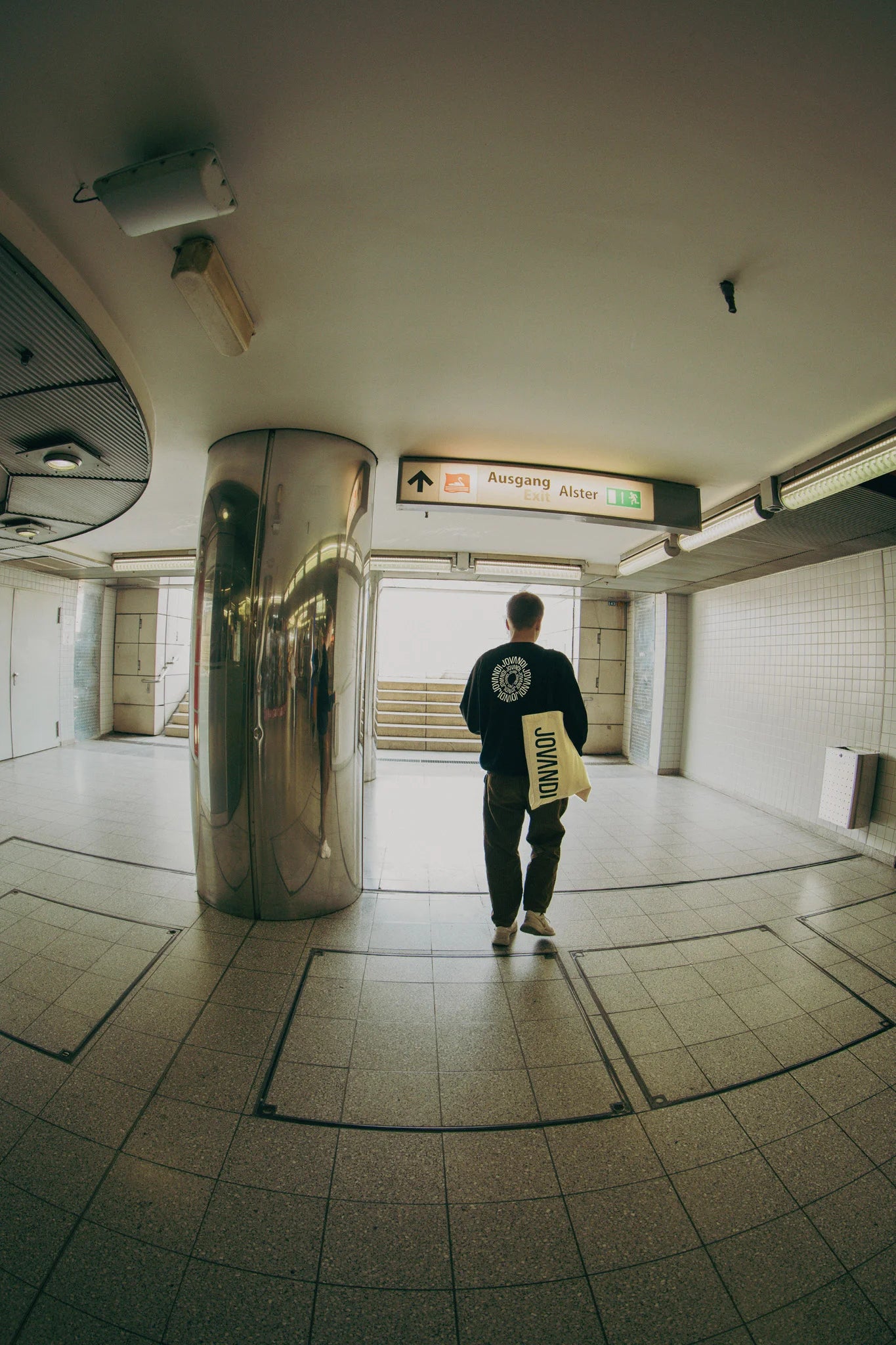 Man with a black Jovandi Circle Sweater walking through a train station in hamburg