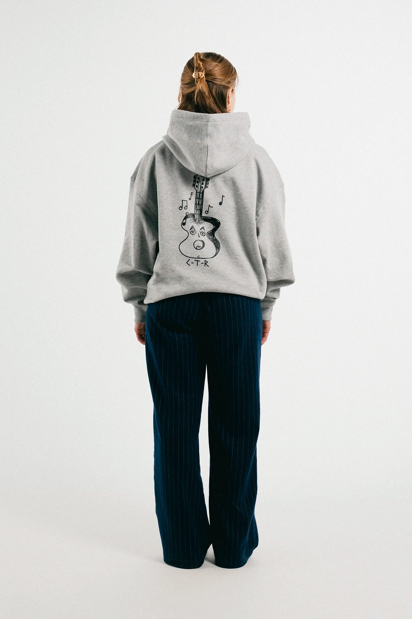 Woma wearing the heather grey Jovandi guitar hoodie