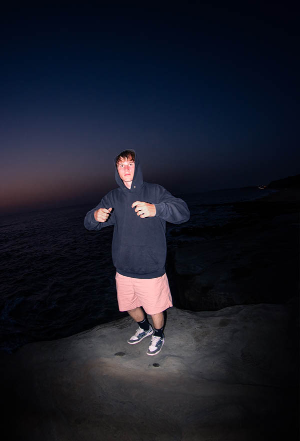 A guy wearing the circle hoodie on a cliff in portugal at night from the front