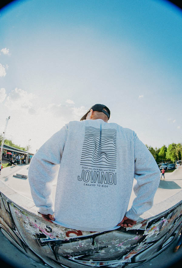 a guy sitting on a quater pipe with the lines sweater