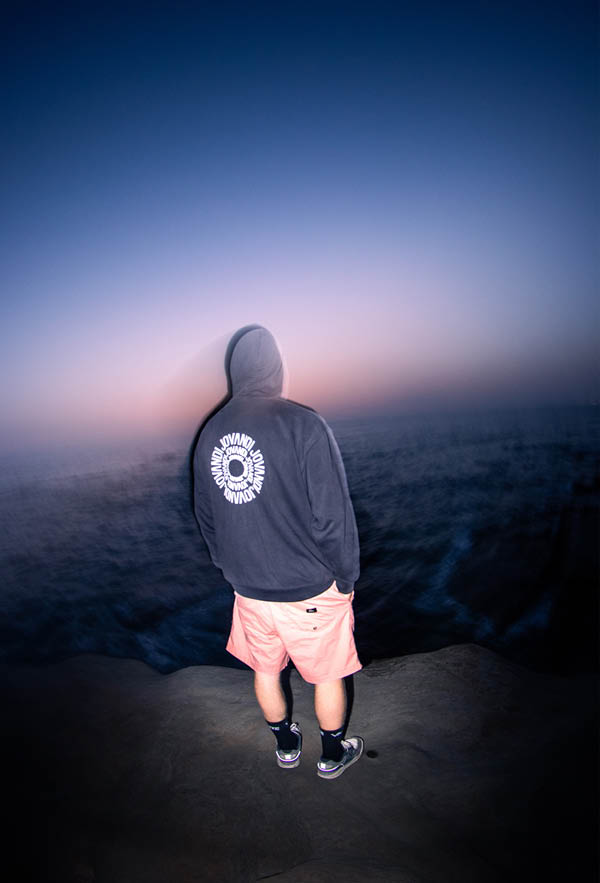 A guy wearing the circle hoodie on a cliff in portugal at night from the back