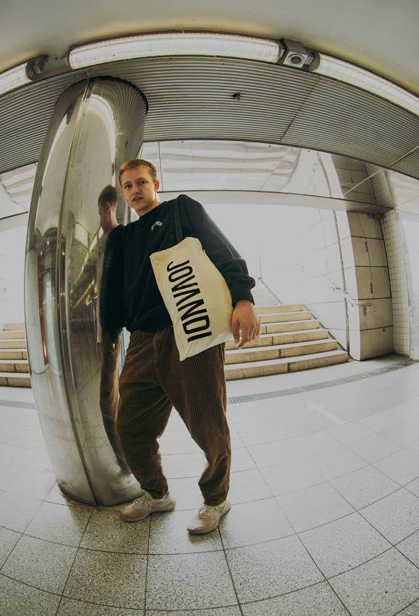 A guy wearing the circle sweater in a train station