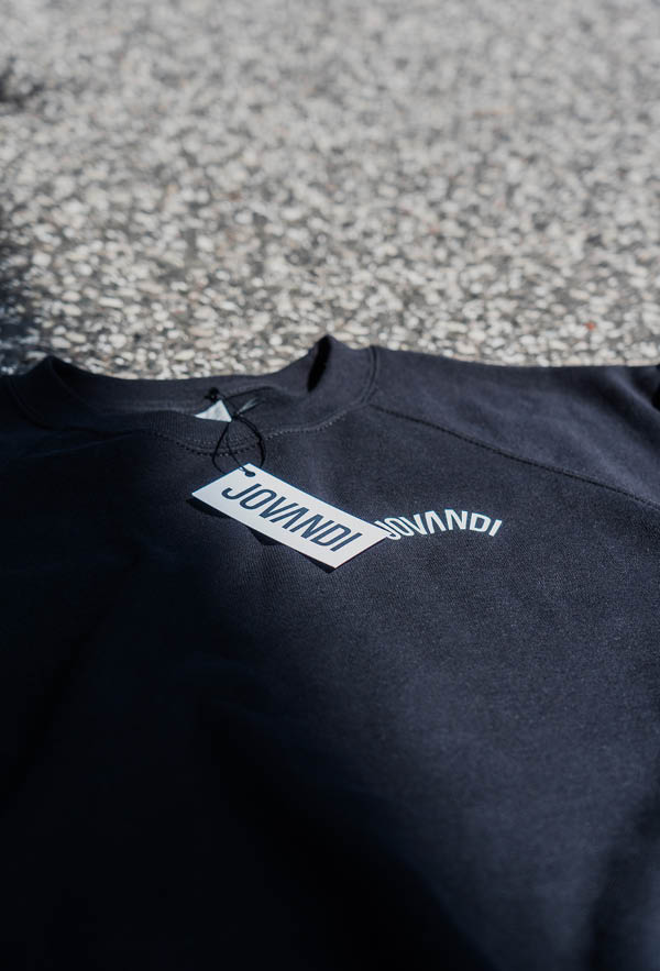 A flatlay closeup of the top of the circle sweater on a asphalt background