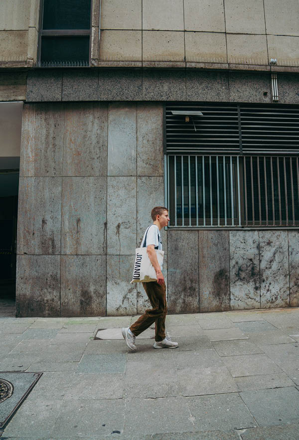 A guy walking with the Basic Bag in front of a concrete wall