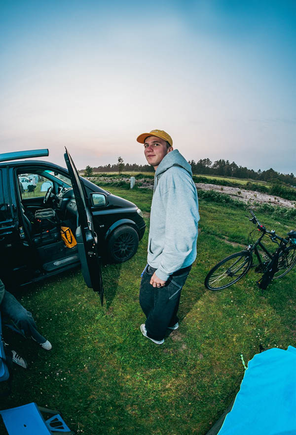 A guy wearing the guitar hoodie on a camping ground in denmark at sunset
