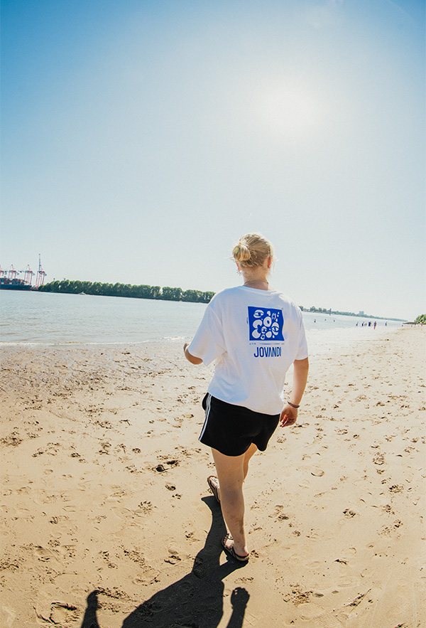 a girl walking down the beaach with the cheyes 1 tshirt