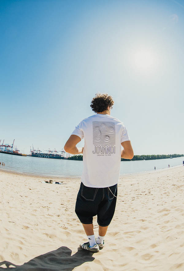 a guy walking down the beach wearing the lines tshirt