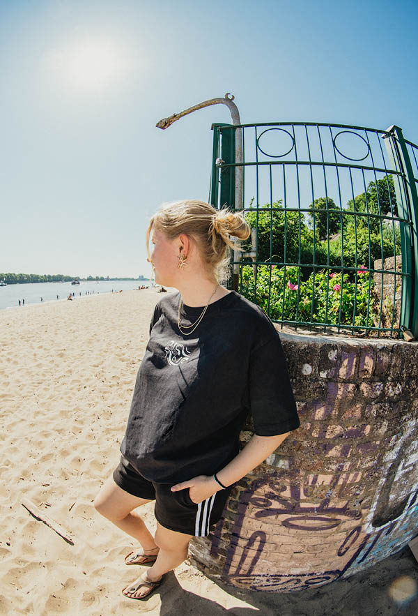 a girl leaning on a corner with graffiti wearing the contrast tshirt