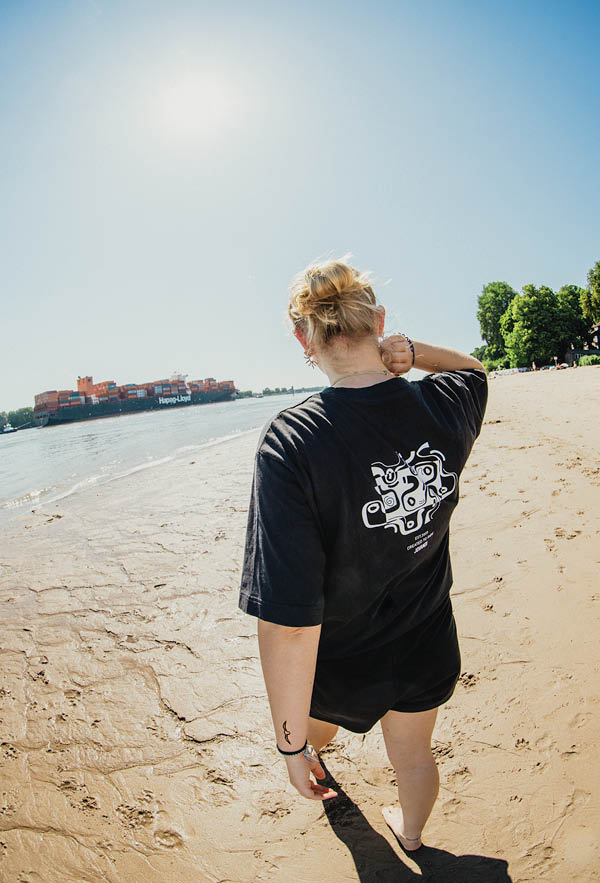 A girl walking on the bach of hamburg wearing the contrast t-shirt from the back
