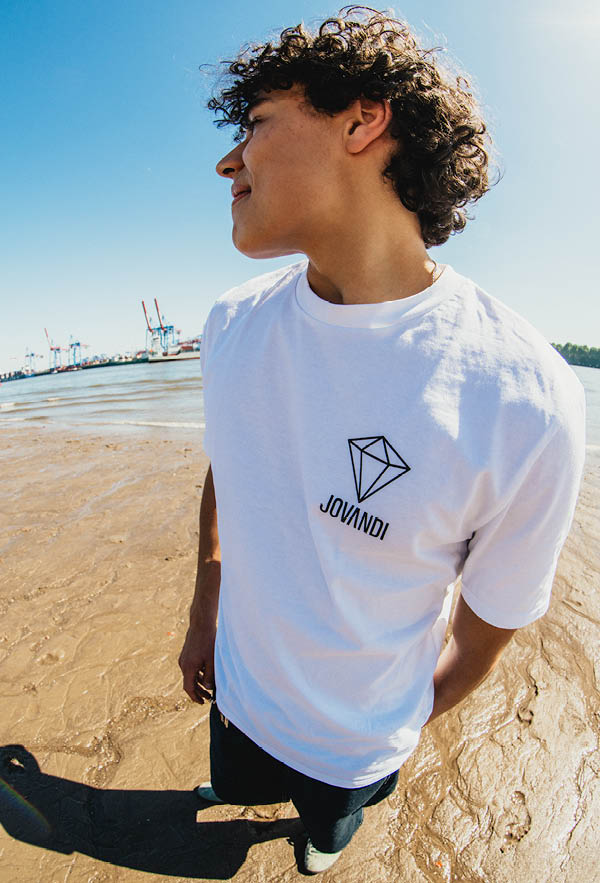 A guy leaning on a wall with grffiti wearing the diamonds tshirt